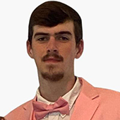 A young man wearing a pink tuxedo and bow tie, posing confidently.