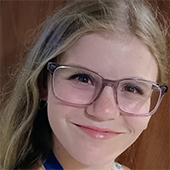 A smiling young girl with glasses, showcasing a cheerful expression.