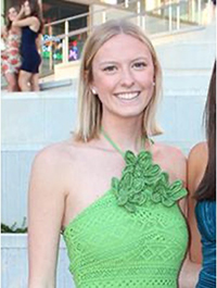 A young woman smiling in a green halter-neck dress at a social event.