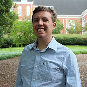 Smiling student in outdoor garden area.