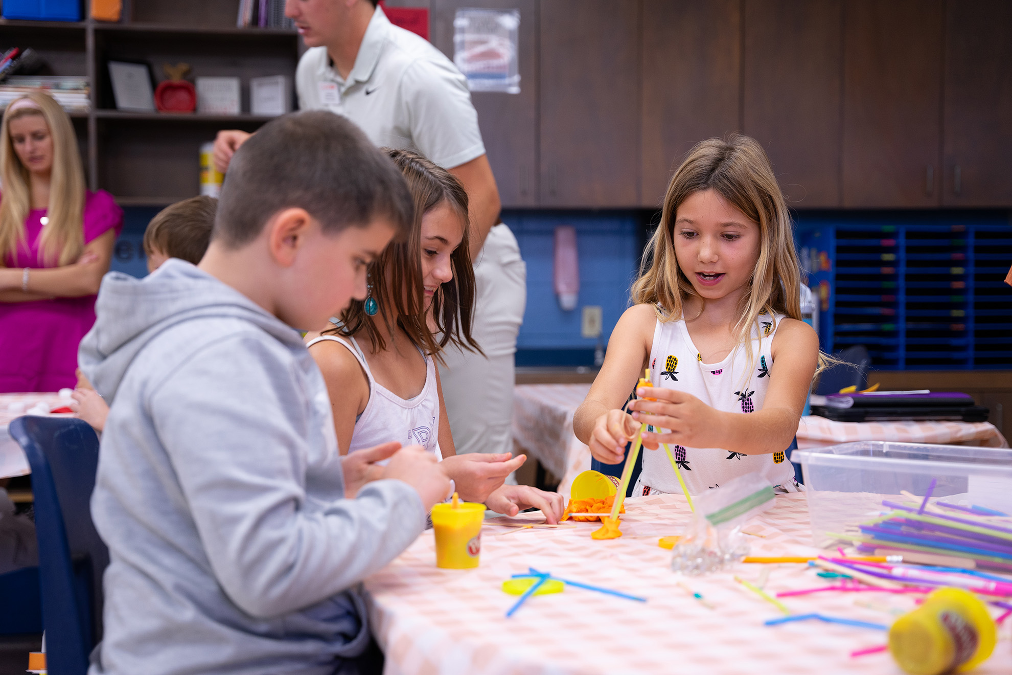 Children engaged in a creative activity with colorful play dough and craft supplies in a classroom setting.