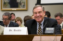 Dr. Bodde smiling as he sits at a desk with his nametag visible at the front of the table