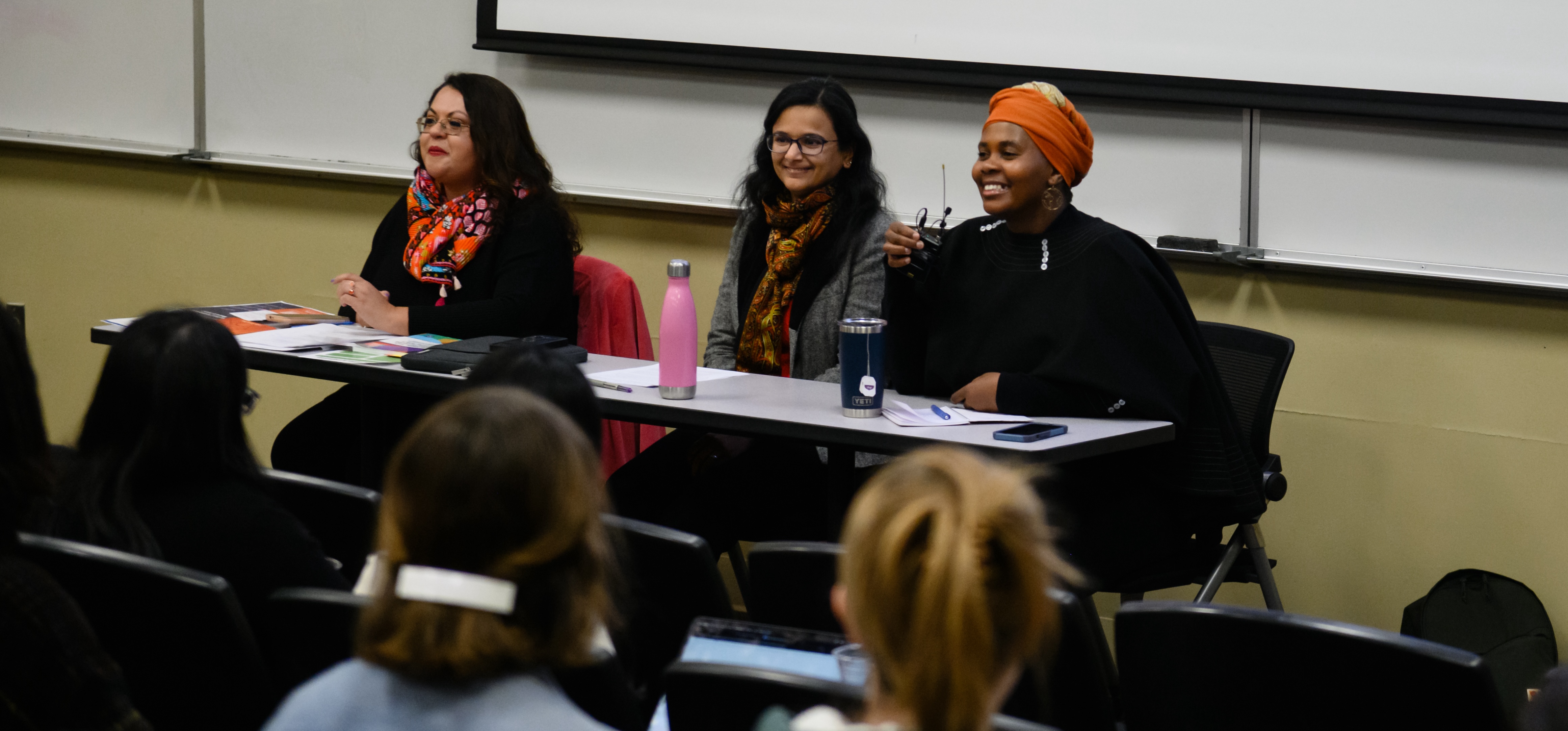 Three women seated at a table facing an audience; all panelists for the event