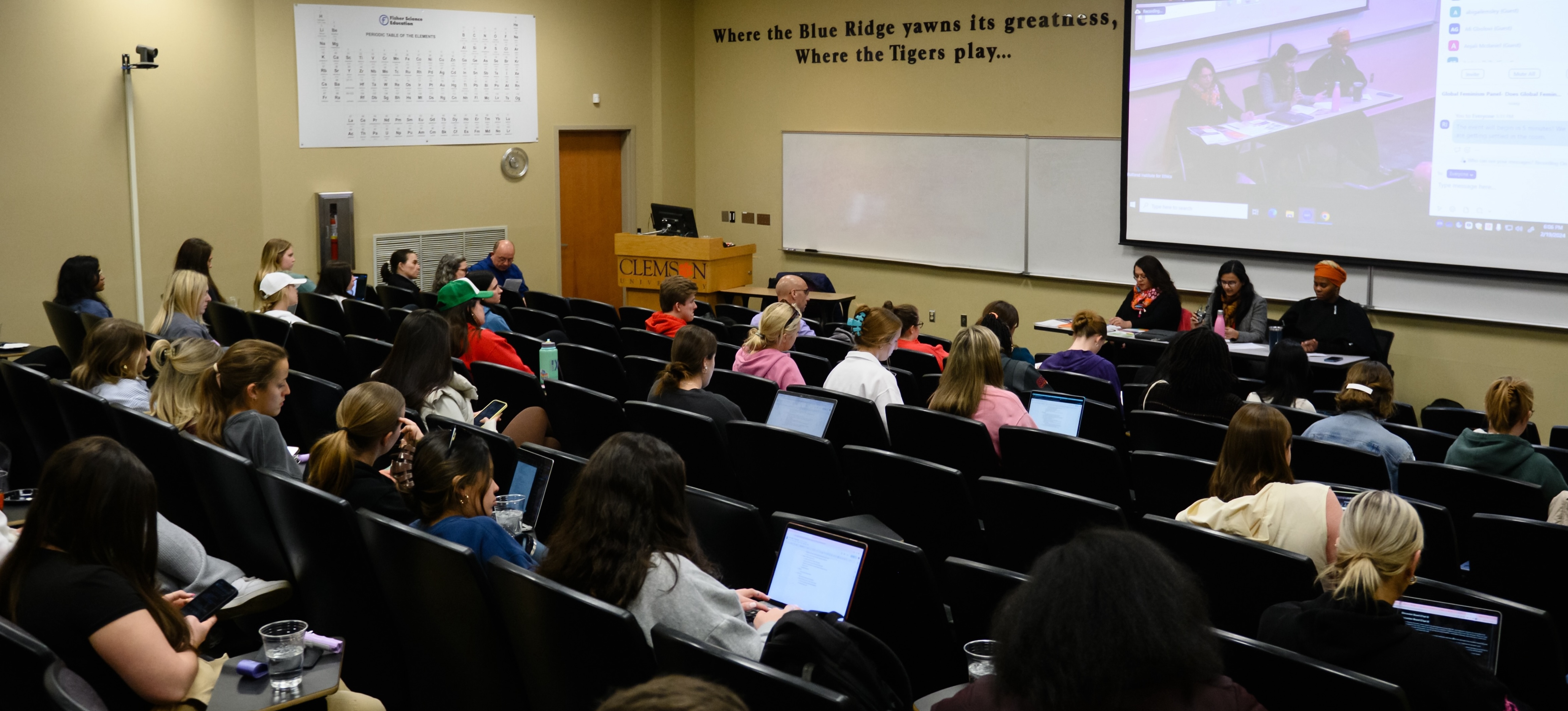 Wide shot of auditorium of students listening to panelists at the front of the room