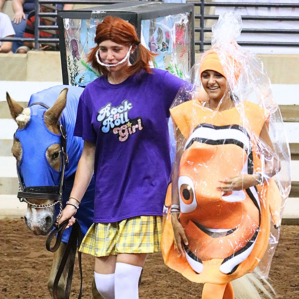 2 girls in costumes walking with a horse