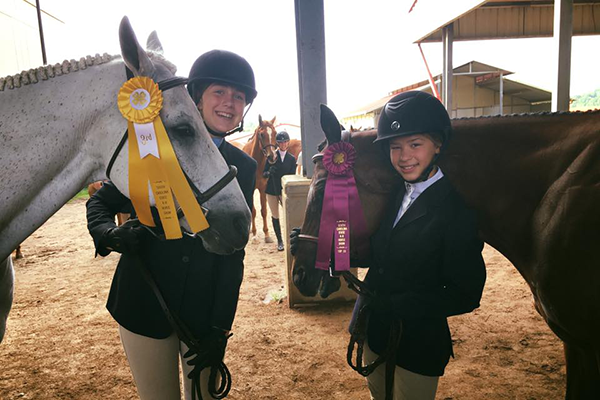 Two girls with their horses and prize ribbons