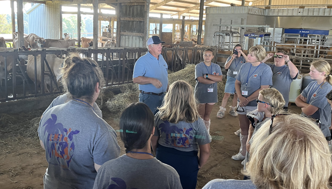 adults presenting to a group of students in a barn