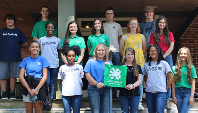 Group photo of students posing on steps and holding a 4 h flag
