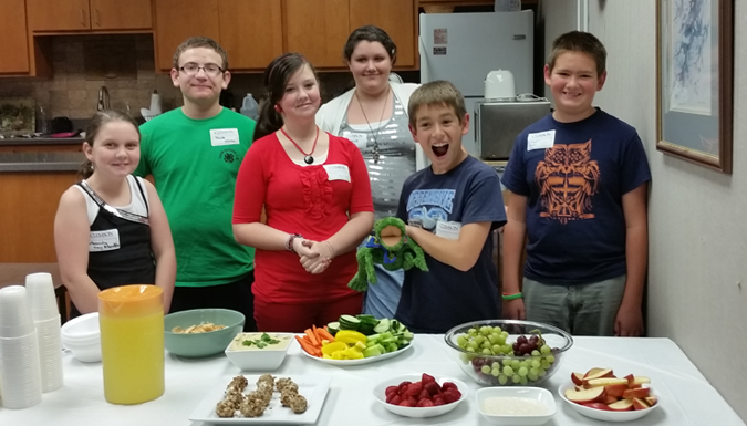 students posing behind a table of prepared food