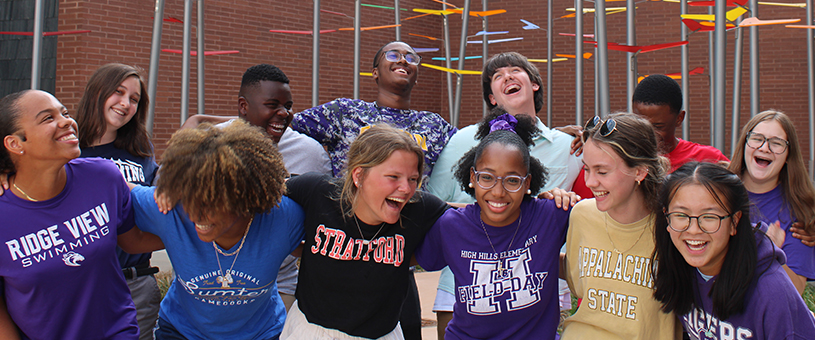 group of students posing arm in arm and laughig