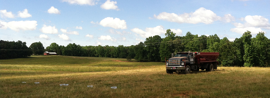 Image of a solid manure spreader truck in a pasture about to begin spreading.