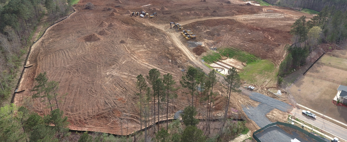 aerial view of large construction site with work trucks and exposed soil