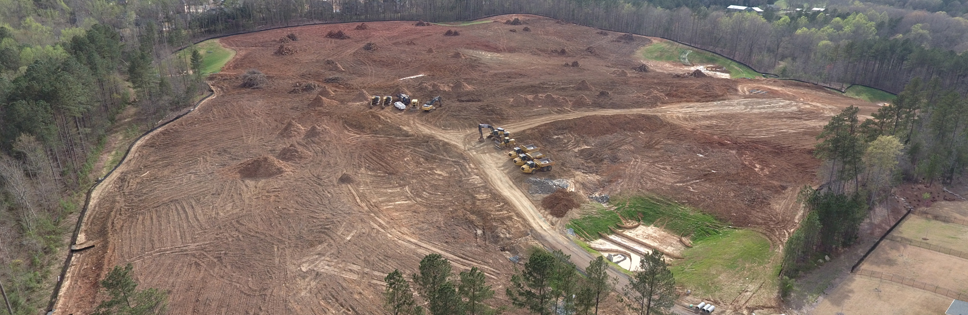 aerial view of a large construction site with exposed soil and work trucks
