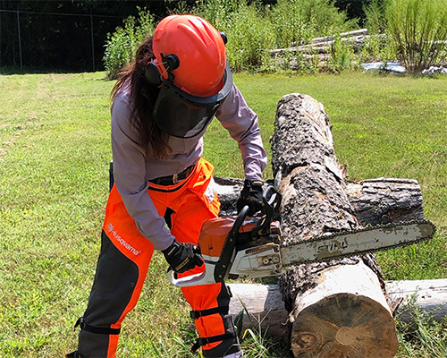 person cutting log with chainsaw