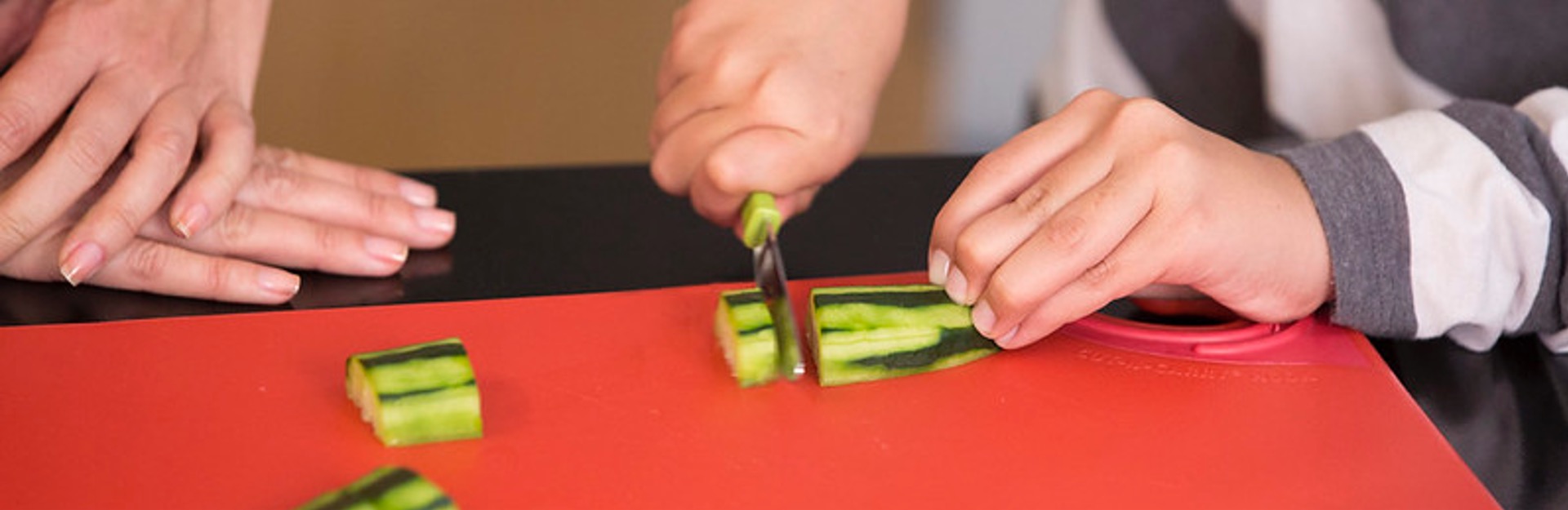 close up of hands cutting a cucumber