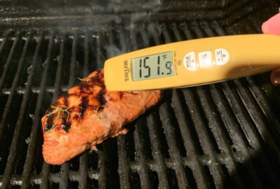 digital thermometer in meat on an open grill