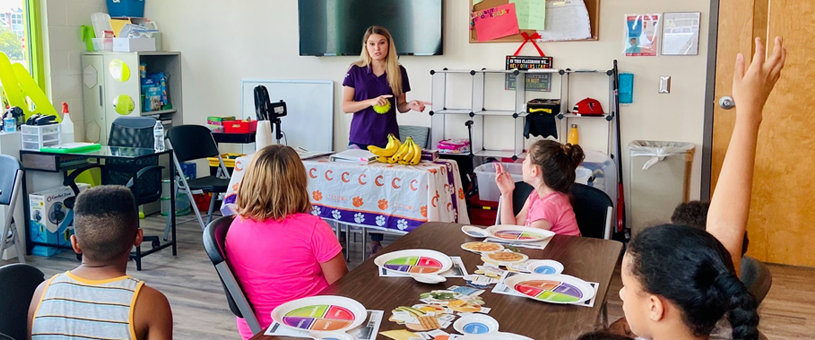 Woman stands in front of group of students in a classroom