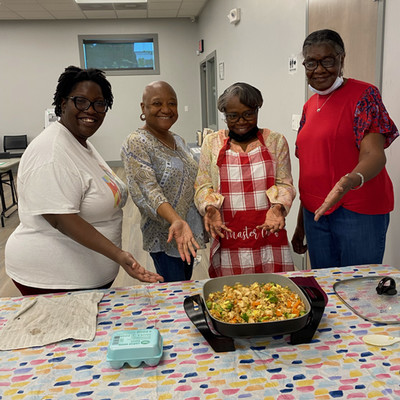 4 women standing behind a food prep table