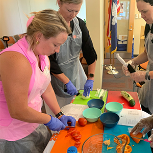 women standing at a table learning to properly use a knife in the kitchen