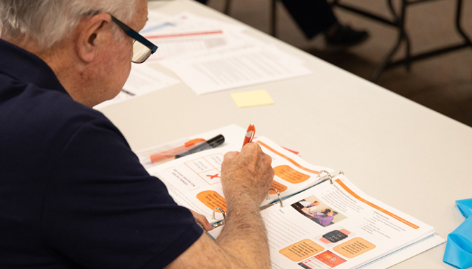 view over the shoulder of an older gentleman looking at a curriculum booklet