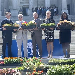 students and government officials standing on the sc state house stairs holding flower arrangements