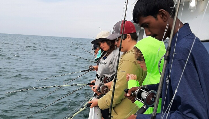 teenage boys fishing off a boat in the ocean