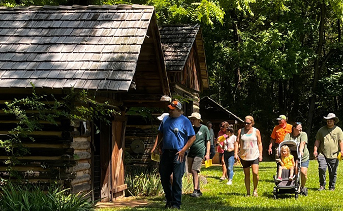families on the summer tour viewing log cabins on a sunny day