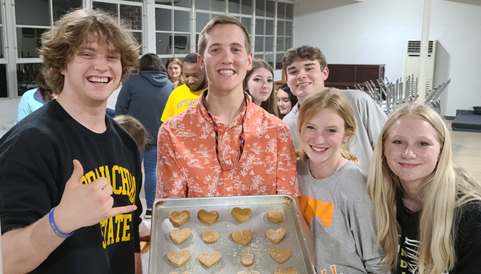 vet camps students in a kitchen holding a pan of home made dog treats