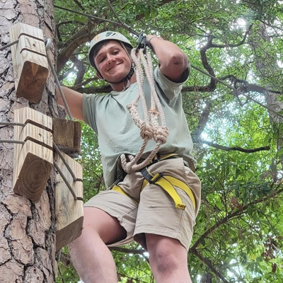 student harnesses into a high ropes team challenge element