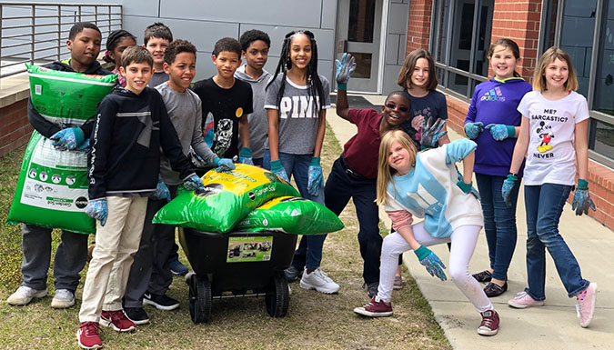 school kids posing with garden supplies