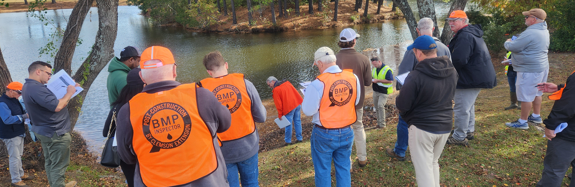 post bmp inspector course participants holding clipboards and looking toward a creek