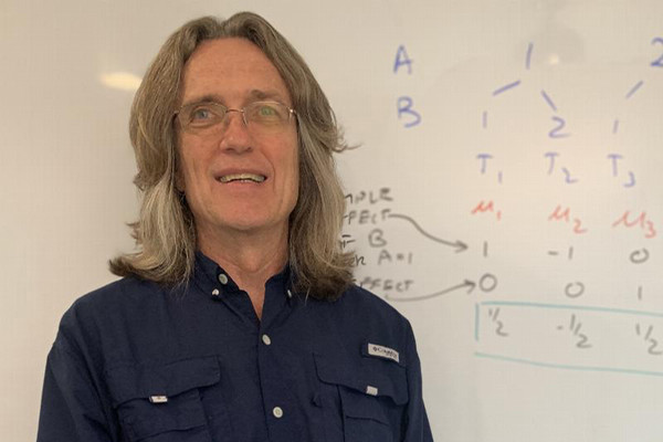 Dr. Bridges smiling in front of a white board.