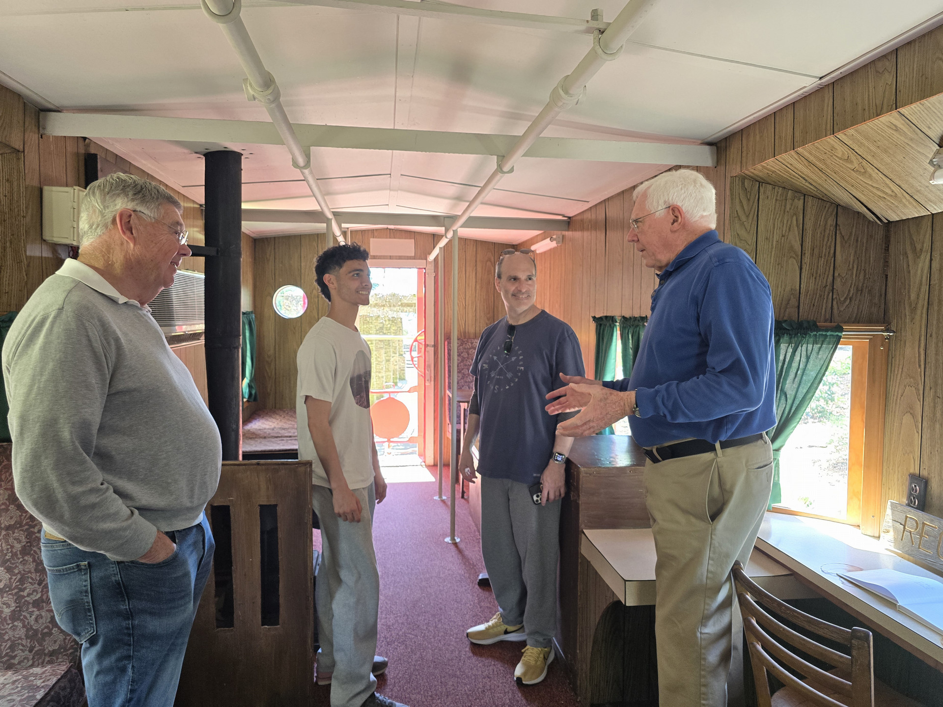 group of men speaking while touring the inside of the Class of '39 caboose