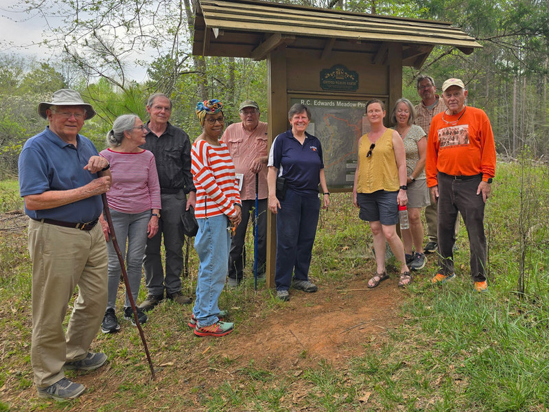 Social group standing in front of the R.C Edwards Meadow Project trail sign