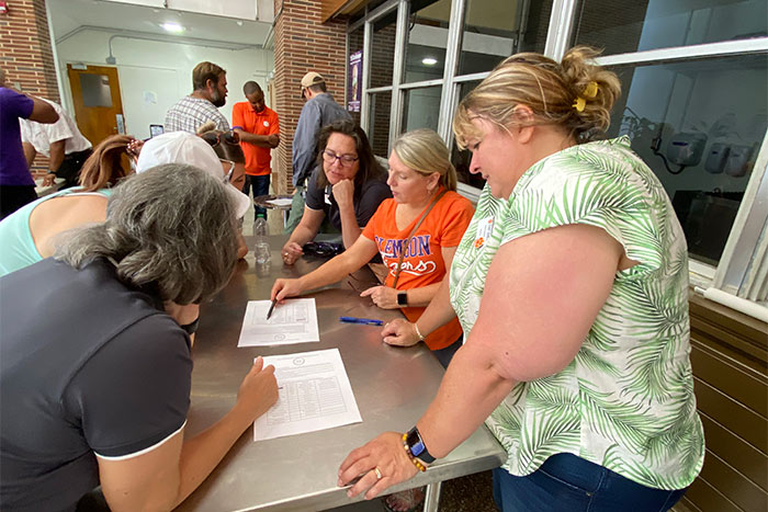 A team of staff gather around a table discussing a worksheet