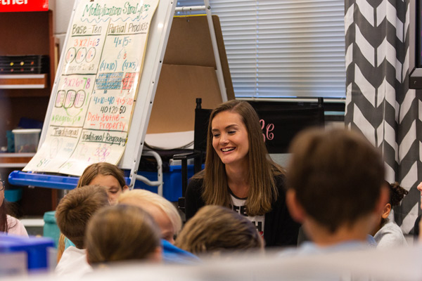 A student teacher address a class of elementary students