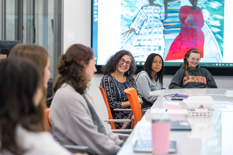 A professor sits at a table with her students during a class