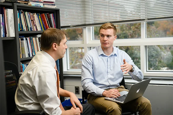 A grad student discusses with a professor in their office