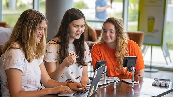 Three female students work on an engineering project at a table together