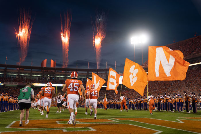 student athletes on the football team run out on the field at the start of a game