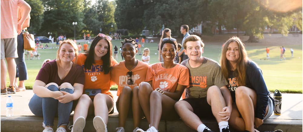 freshman students site on the sidewalk together for the first friday parade