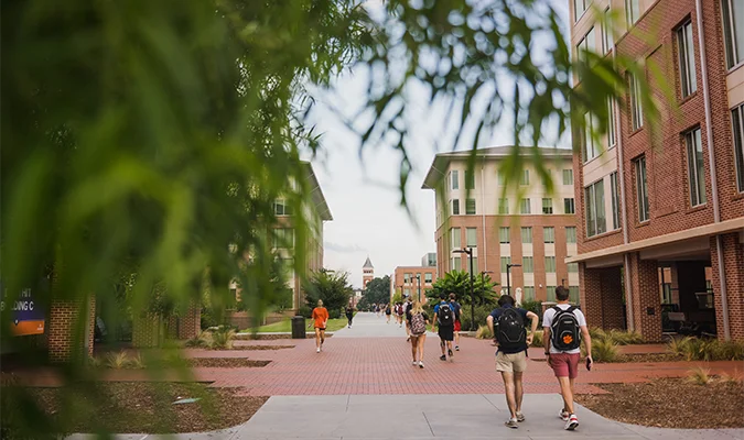 Groups of students walk in a scattered line as they head toward their classes on campus.