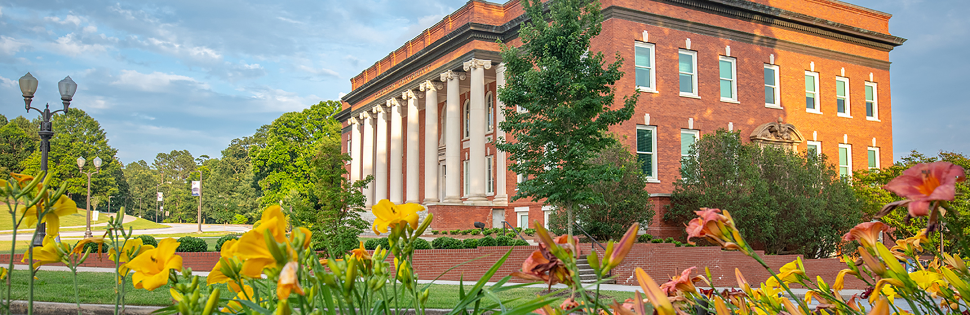 Wide exterior image of Sikes Hall on Clemson's campus at sunset with flowers in the foreground