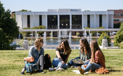 A group of students sit and socialize on the green