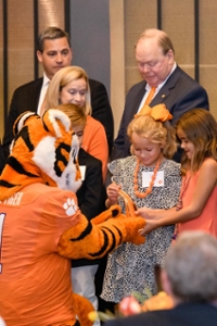 The tiger mascot shakes hands with children at a giving event