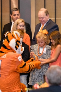 The tiger mascot shakes hands with children at a giving event