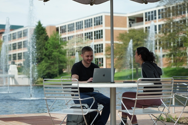 Two pairs of students sit at an outdoor table