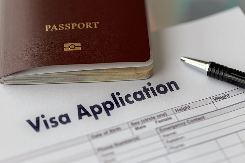 A passport and a visa application form with a pen, highlighting the process of applying for travel documentation.