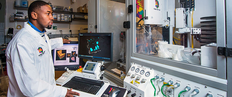 Man in lab jacket controlling a robot. 