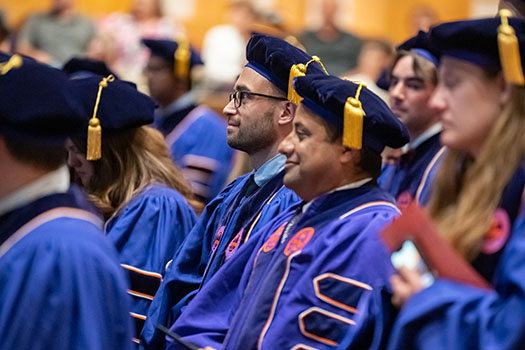 Smiling students look towards the stage at their doctoral hooding.